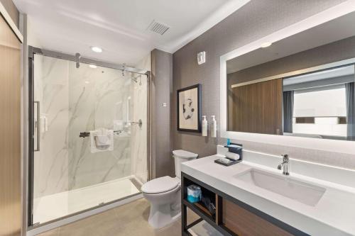 歐文的住宿－Embassy Suites By Hilton Irving Las Colinas，带淋浴、盥洗盆和卫生间的浴室