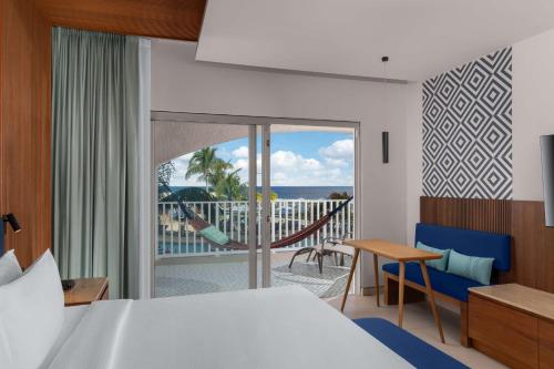 1 Schlafzimmer mit einem Bett und einem Balkon mit einer Hängematte in der Unterkunft Hilton Cancun Mar Caribe All-Inclusive Resort in Cancún