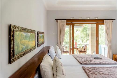 a bedroom with a large white bed and a window at Artja Inn Ubud in Ubud
