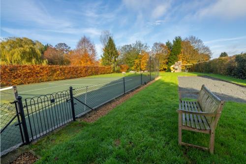 a wooden bench sitting next to a tennis court at Hill Farm Massingham in Little Massingham