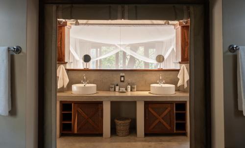 baño con 2 lavabos y ventana en Tuli Safari Lodge Mashatu, en Lentswelemoriti