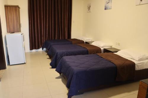 Cette chambre comprend 3 lits et un réfrigérateur. dans l'établissement Sejan hotel, à Aqaba