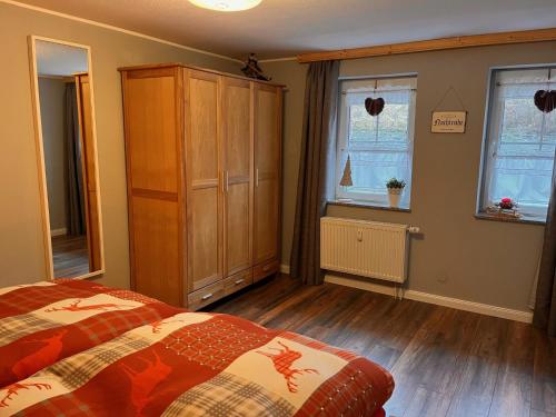 a bedroom with a bed and a cabinet and two windows at Ferienwohnung Hexenstube 2 in Tanne