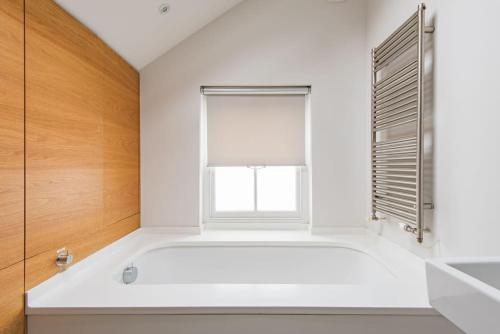 a white bathroom with a bath tub and a window at Starboard Light in Whitstable