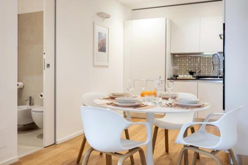 a white kitchen with a white table and chairs at Luna di mare - nuovo appartamento sul mare in Acireale