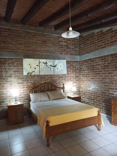 1 dormitorio con cama y pared de ladrillo en Cabaña sol y campo en Guaymallén
