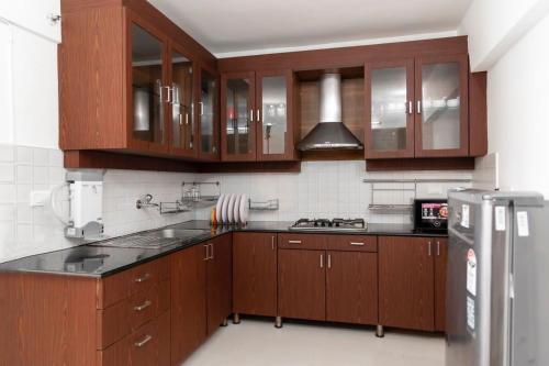 een keuken met houten kasten en een roestvrijstalen koelkast bij Best sea view serviced apartments at marine drive cochin in Cochin