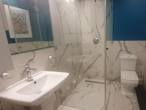 La salle de bains blanche est pourvue d'un lavabo et d'une douche. dans l'établissement City Center by Better Place, à Varsovie