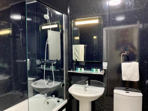 a bathroom with a sink and a toilet and a mirror at Sarum Apart-Hotel in Saint Helier Jersey