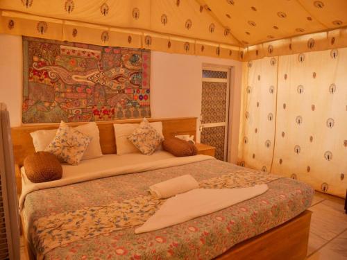 a bedroom with a bed with a tapestry on the wall at Excellent Desert Safari camp in Sām