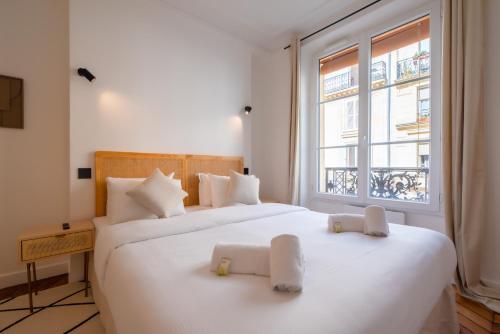 une chambre avec deux lits avec des draps blancs et une fenêtre dans l'établissement Lovely apartment Near Canal St Martin, à Paris