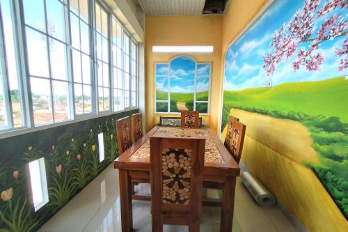 un comedor con una mesa y una pintura en la pared en ZAHIRA GUESTHOUSE, en Palmerah