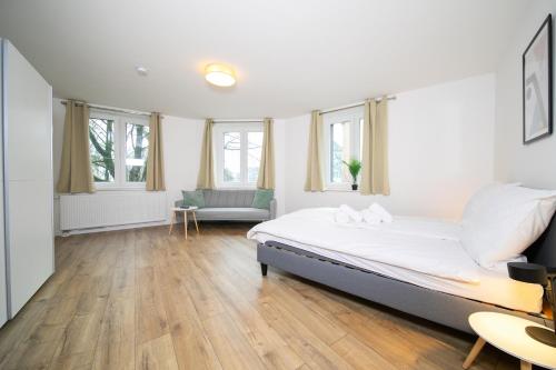 um quarto com uma cama, um sofá e janelas em Stylish Apartments - 71 m² - Zentral - 10 Min Messe em Düsseldorf