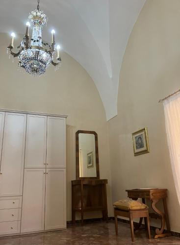 a room with a chandelier and a table and a mirror at Palazzo Prence in Copertino