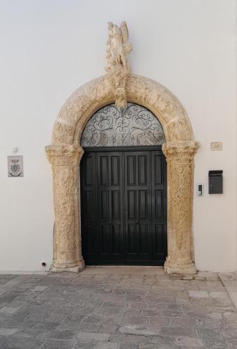 a black door with a cross on top of it at Palazzo Prence in Copertino