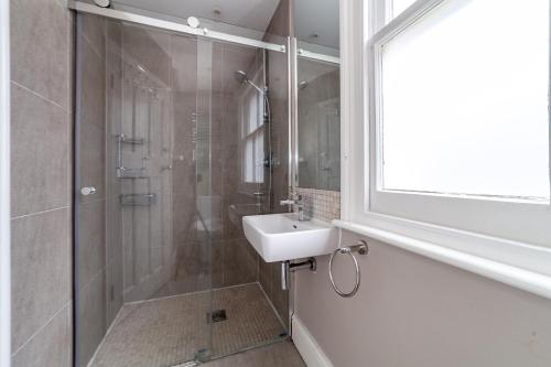 a bathroom with a shower and a sink and a glass shower stall at The Hammersmith Villa in London