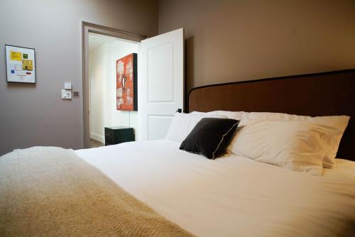 uma grande cama branca com uma almofada preta em The Mary Beth Hotel & Gallery em Nova Orleans