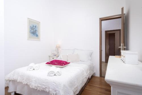 a white bedroom with a bed with shoes on it at Luxury Apartment Flora, Stari Grad, Hvar Island in Stari Grad