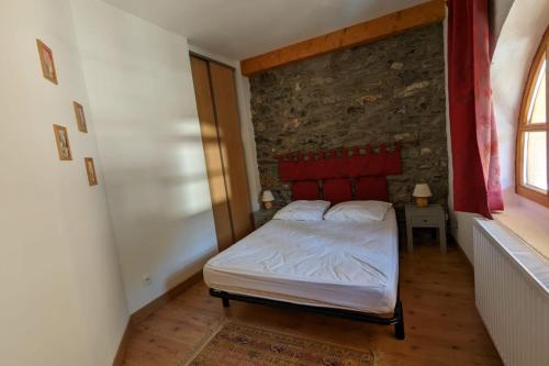Un dormitorio con una cama y una pared de piedra. en Gîte Neige Cordier - Villar d'Arène center 2 bedrooms and large terrace, en Villar-dʼArène