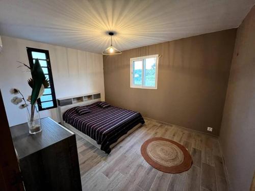 ein Schlafzimmer mit einem Bett und einer Vase aus Blumen in der Unterkunft Jolie petite maison à la campagne in Le Moule