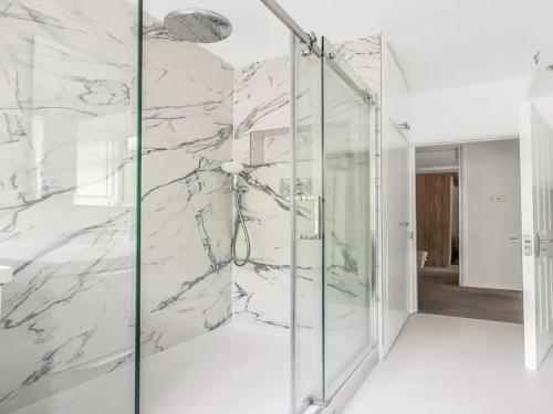 a glass shower in a bathroom with marble walls at Pass the Keys Battersea Hideaway in London