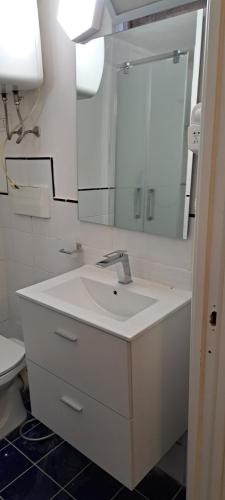 biała łazienka z umywalką i lustrem w obiekcie Studio Bandiera apartment w mieście Palermo