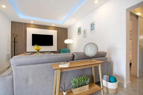 a living room with a gray couch and a tv at El Ramonal Vacacional in Candelaria