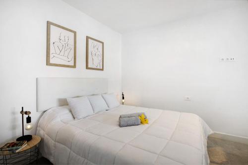 a white bedroom with a white bed with a stuffed animal on it at El Ramonal Vacacional in Candelaria