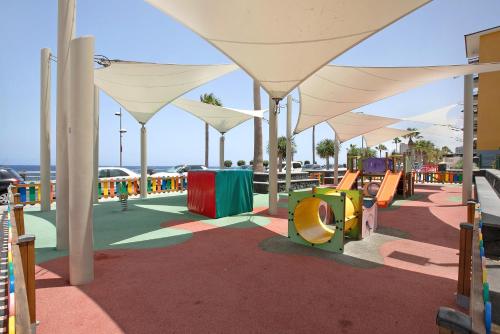 a playground with tables and chairs and umbrellas at El Ramonal Vacacional in Candelaria