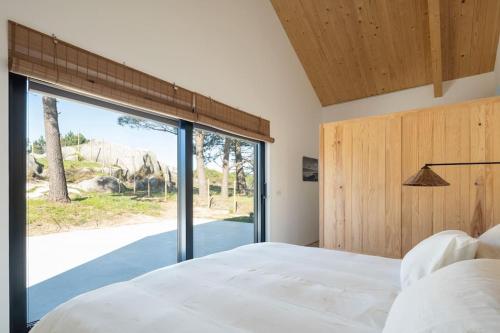 1 dormitorio con cama y ventana grande en itacahomes casa NORO, en Ribeira