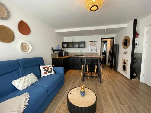a living room with a blue couch and a kitchen at Studio le petit écureuil in Carnac