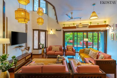 a living room with orange furniture and a flat screen tv at EKOSTAY - Gold -Casa Pino in Candolim
