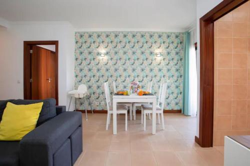 a living room with a couch and a table with chairs at The Albufeira Concierge - Modern Salgados in Albufeira