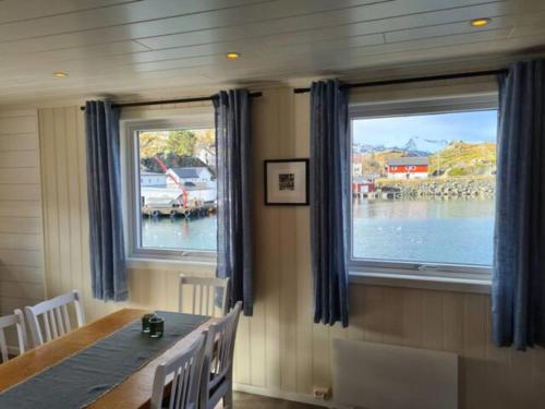 a dining room with a table and two windows at Damperiholmen cabin in Sund