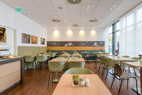 a dining room with tables and chairs and windows at ibis Heilbronn City in Heilbronn