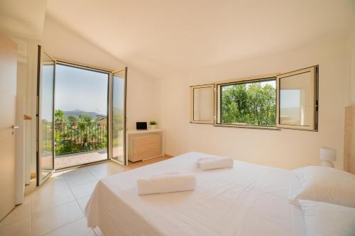 a white bedroom with a large bed and large windows at Villa Trinacria, Piedimonte Etneo in Presa