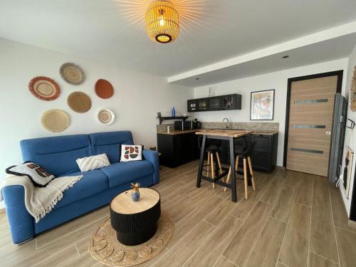 Una sala de estar con un sofá azul y una cocina. en Studio le petit écureuil, en Carnac