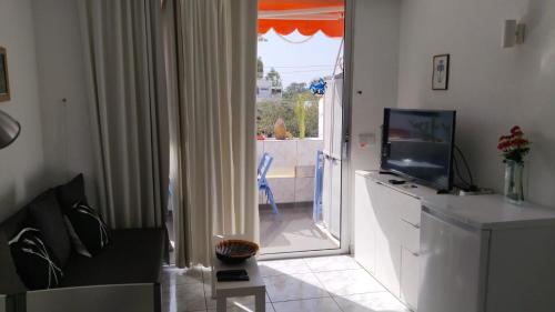 een woonkamer met een tv en een glazen schuifdeur bij EL CHAPARRAL Studio-appartement with fantastic pool- view and STRONG WIFI in Costa Del Silencio