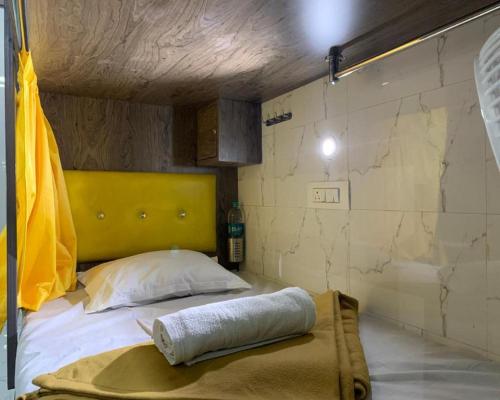 a bed with a yellow headboard in a room at Neenava Dormitory Asalpha in Mumbai