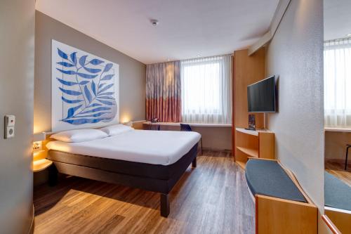 a hotel room with a bed and a tv at ibis Heilbronn City in Heilbronn