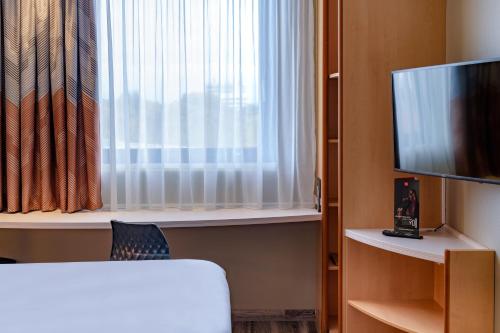 a room with a bed and a tv and a window at ibis Heilbronn City in Heilbronn
