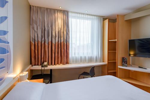 a hotel room with a bed and a window at ibis Heilbronn City in Heilbronn