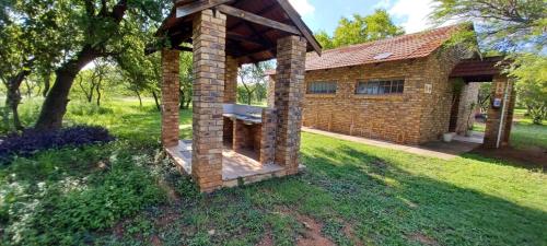 a brick building with a shelter in the grass at El Rancho Grande in Warmbaths