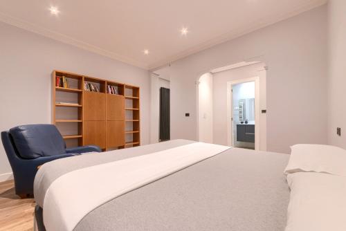 a bedroom with a bed and a blue chair at Encantador apartamento a orillas de la ría in Bilbao