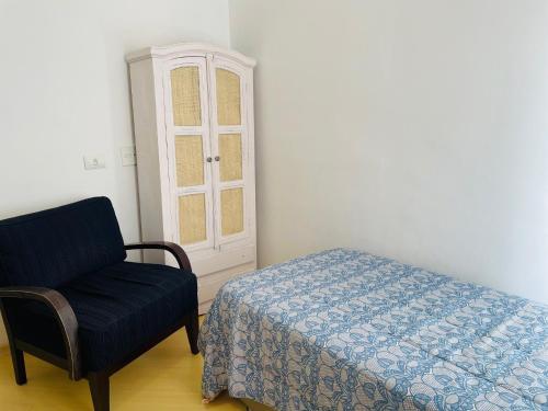 a bedroom with a bed and a chair and a cabinet at Quarto Morumbi - Somente Mulheres in Sao Paulo