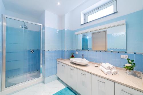 a blue bathroom with a sink and a shower at Villa Trinacria, Piedimonte Etneo in Presa