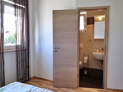 ein Bad mit einer Tür, die zu einem Waschbecken führt in der Unterkunft Apartments Rea in Šilo
