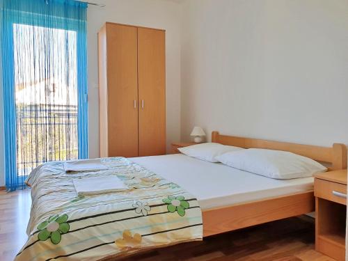 ein Schlafzimmer mit einem Bett und einem großen Fenster in der Unterkunft Apartments Rea in Šilo