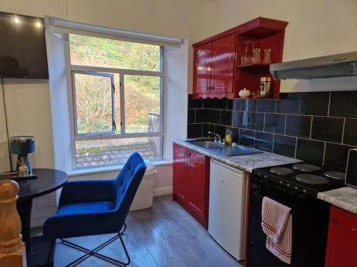 a kitchen with red cabinets and a blue chair and a table at Ideal for short stays in Cork