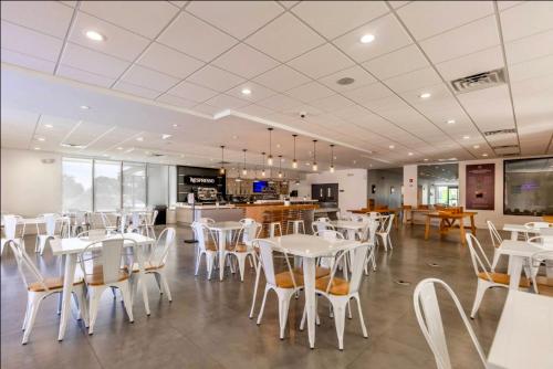 a dining room with white tables and chairs at Pool - WiFi - Parking - Best Location ! in Kissimmee